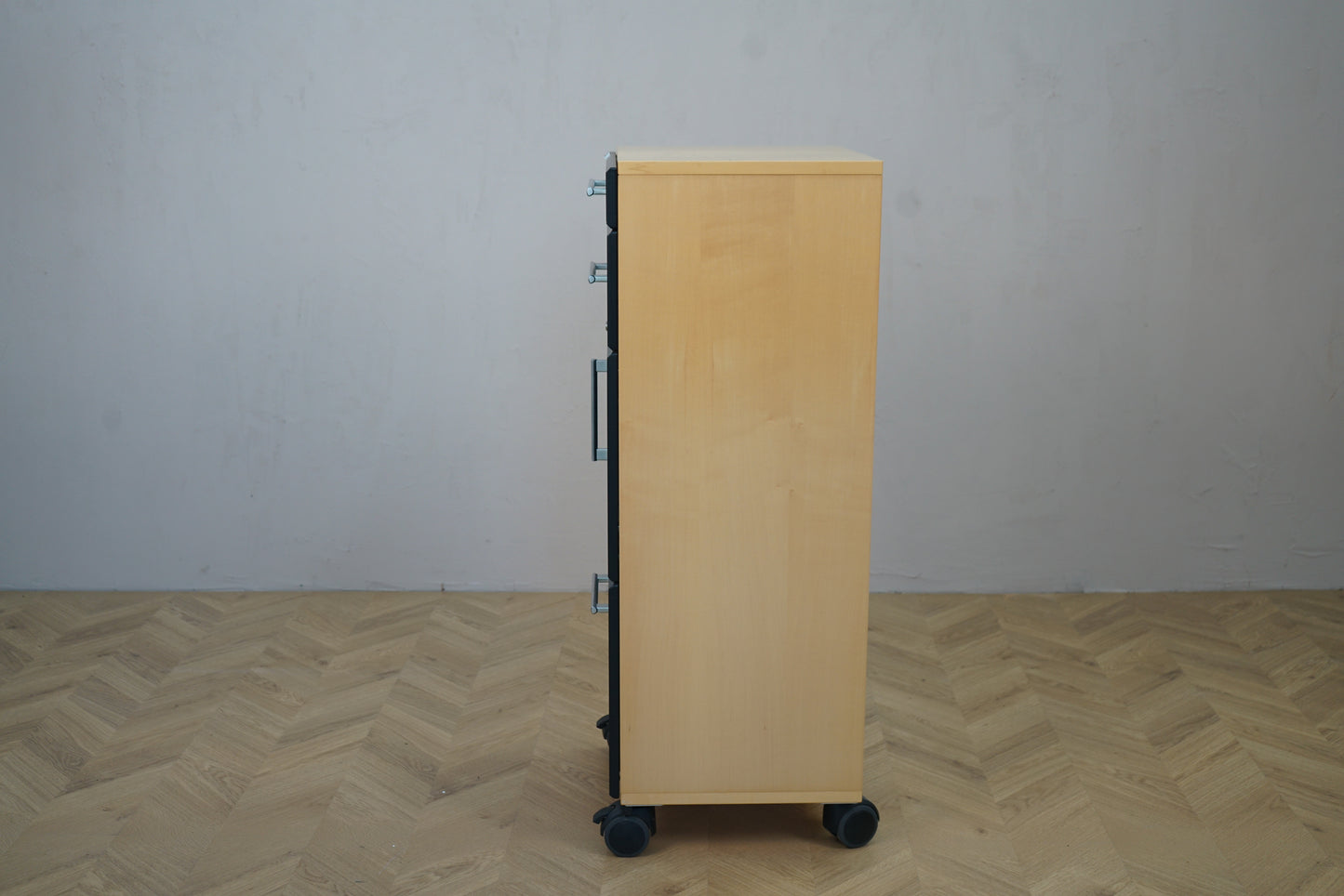 Smalt opbevaringsskab på hjul – set fra siden, moderne design i lys træ med sorte fronter, 46x38x111 cm