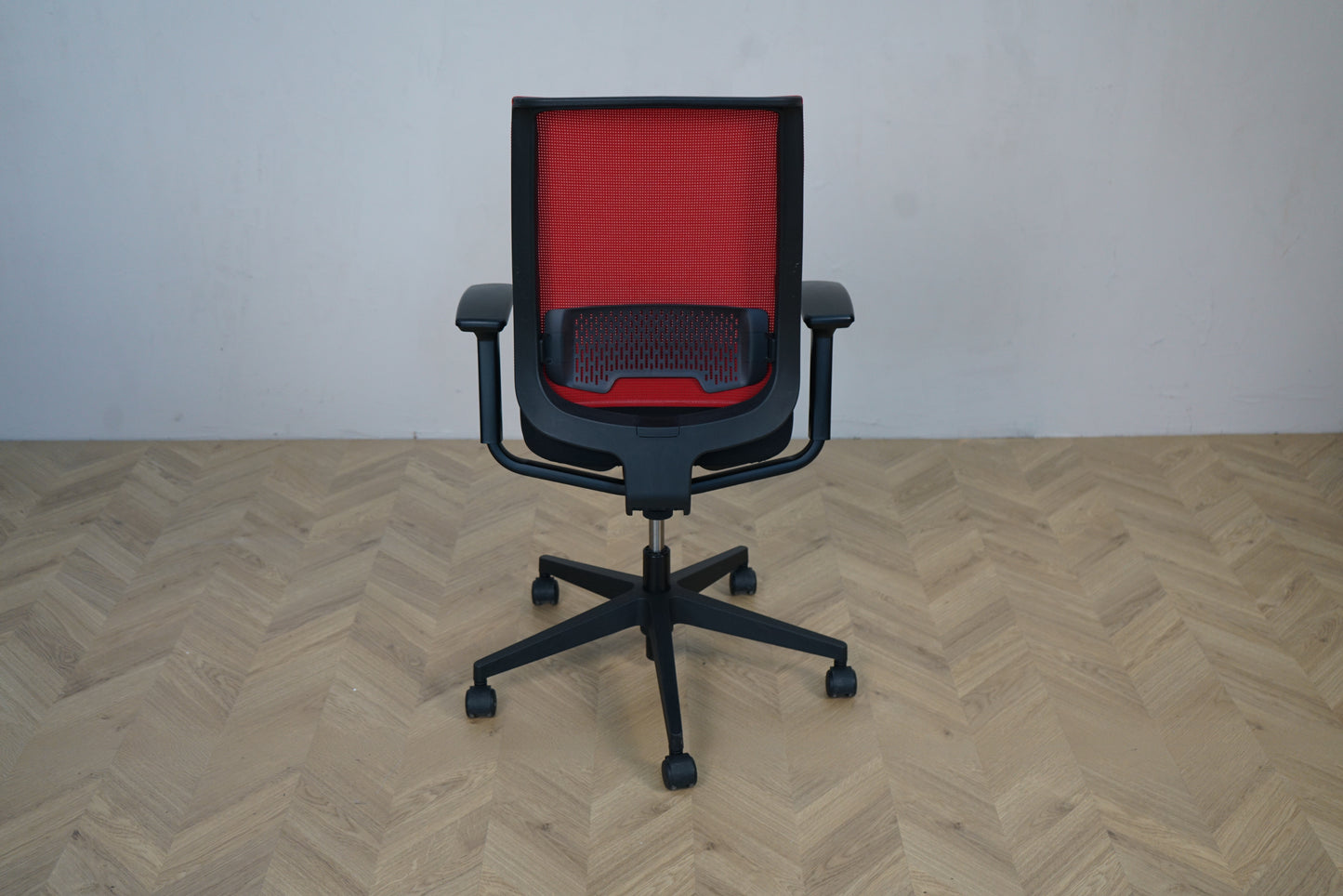 Steelcase kontorstol set bagfra – rød mesh-ryg og robust sort stel med hjul
