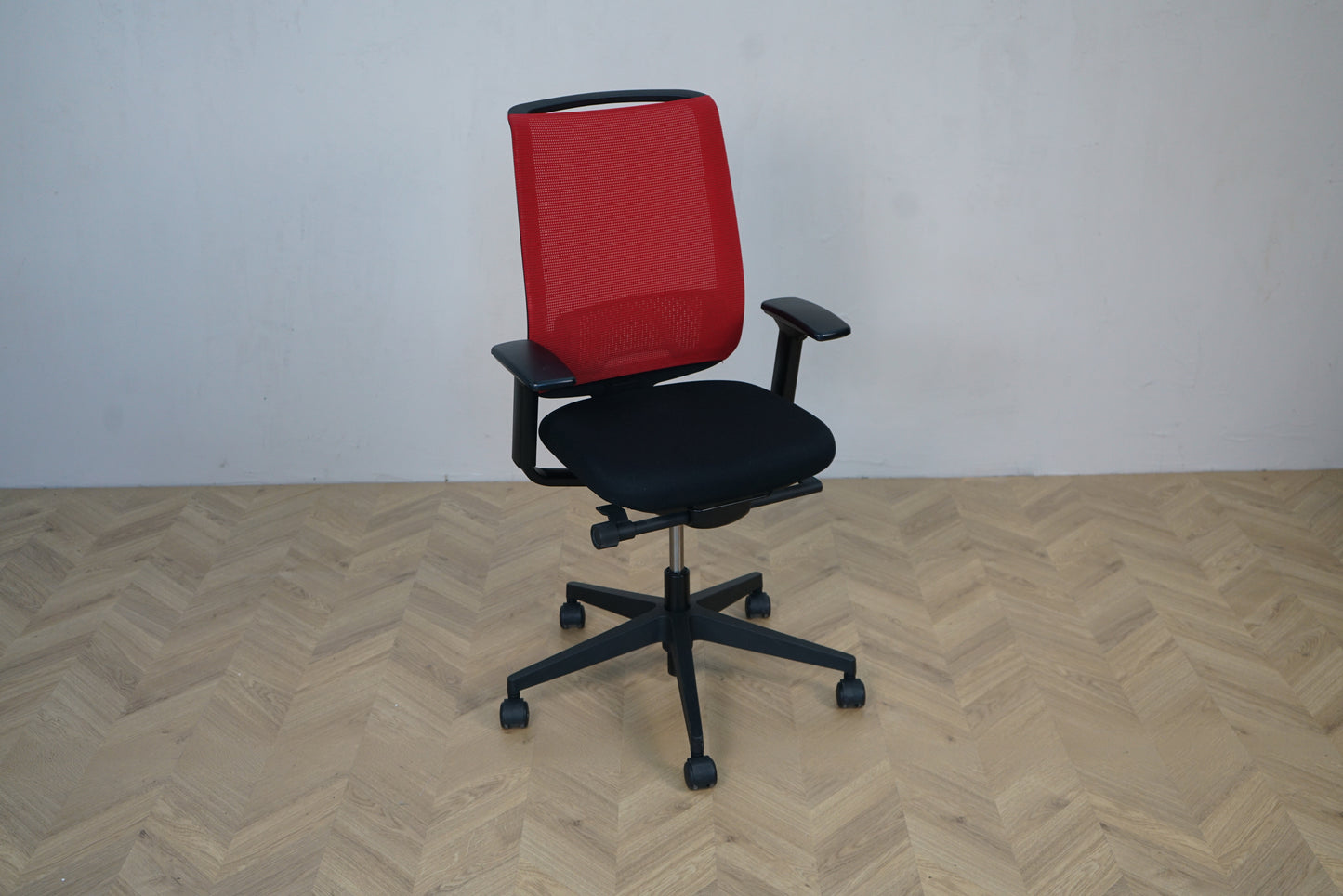 Steelcase kontorstol i skrå vinkel – moderne design med rød ryg og sort polstret sæde