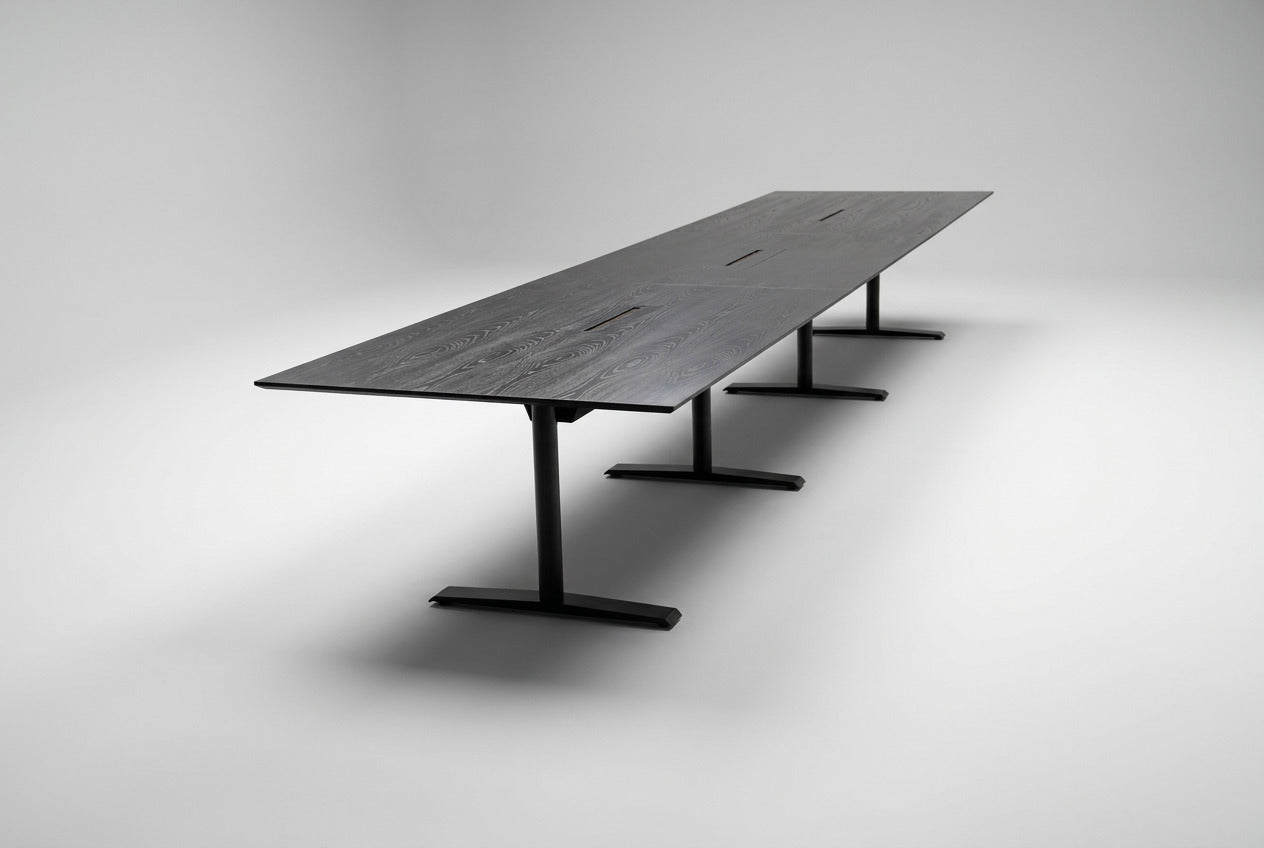 Stort konferencebord i sort eg med sort stel, affaset kant og kabelgennemføringer, 500x120 cm, set fra skrå vinkel.