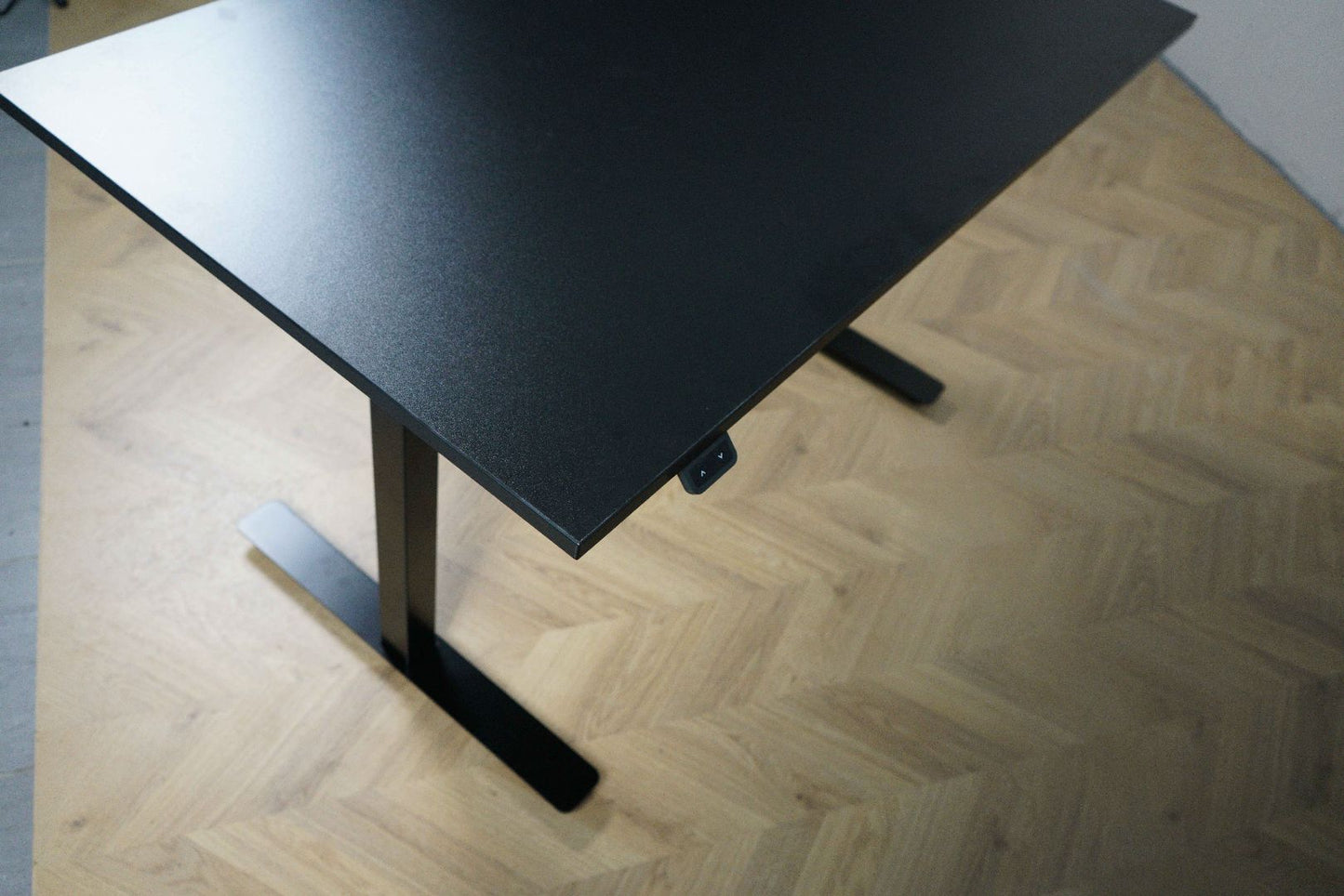 Nærbillede af hæve-sænkefunktion og bordkant på Sweds skrivebord 120x70 cm i sort