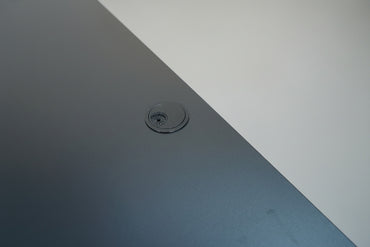 Close up af Swedstyle hæve-sænkebord med sort laminatbordplade, kabelgennemføring og flot finish.
