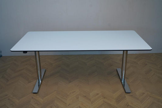 Triumf hæve-sænkebord set forfra med hvid HPL-bordplade, sorte affasede kanter og runde ben. Elegant elektrisk skrivebord i 160x80 cm.