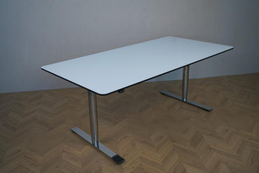 Skrå vinkel af Triumf hæve-sænkebord i hvid HPL med sortlakerede kanter og runde ben. Elektrisk justerbart skrivebord, 160x80 cm, i moderne design.