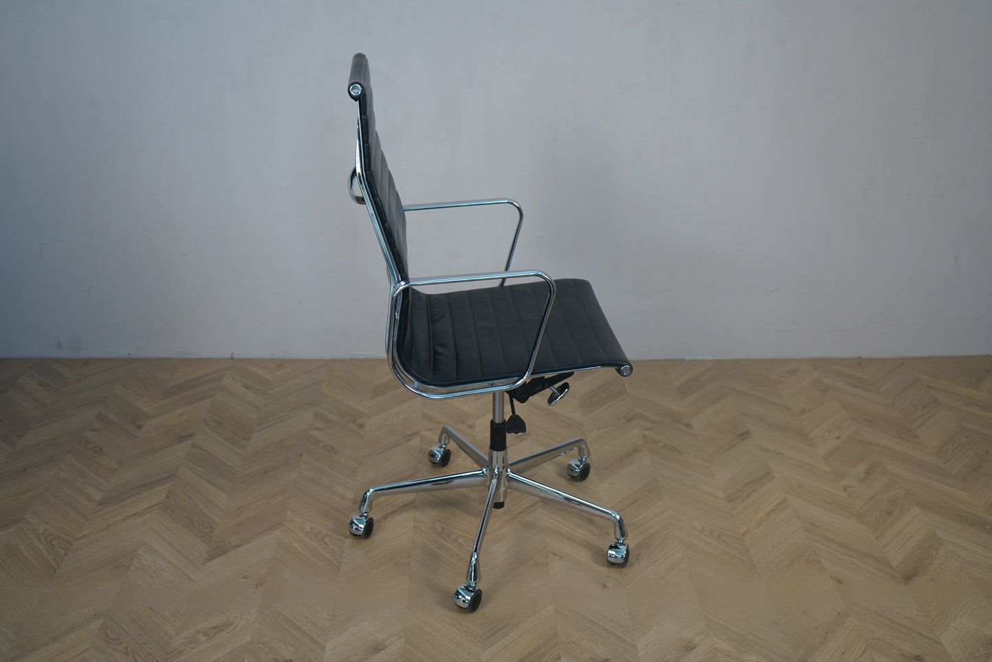 Vitra EA 119 kontorstol set fra skrå vinkel – sort læder, krom stel og klassisk Eames design