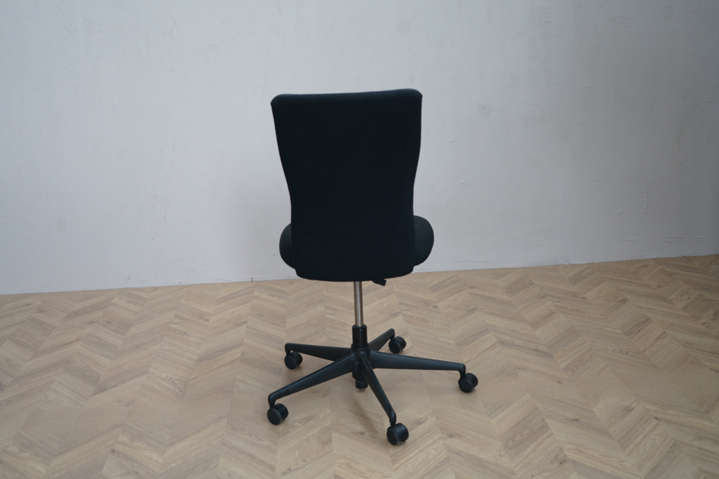 Bagfra visning af Vitra ID Trim kontorstol i sort uden armlæn med solid konstruktion og polstret ryglæn.
