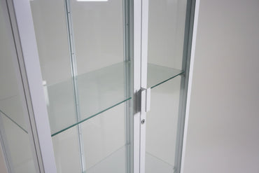 Detalje af hvidt vitrineskab med glashylder og lås