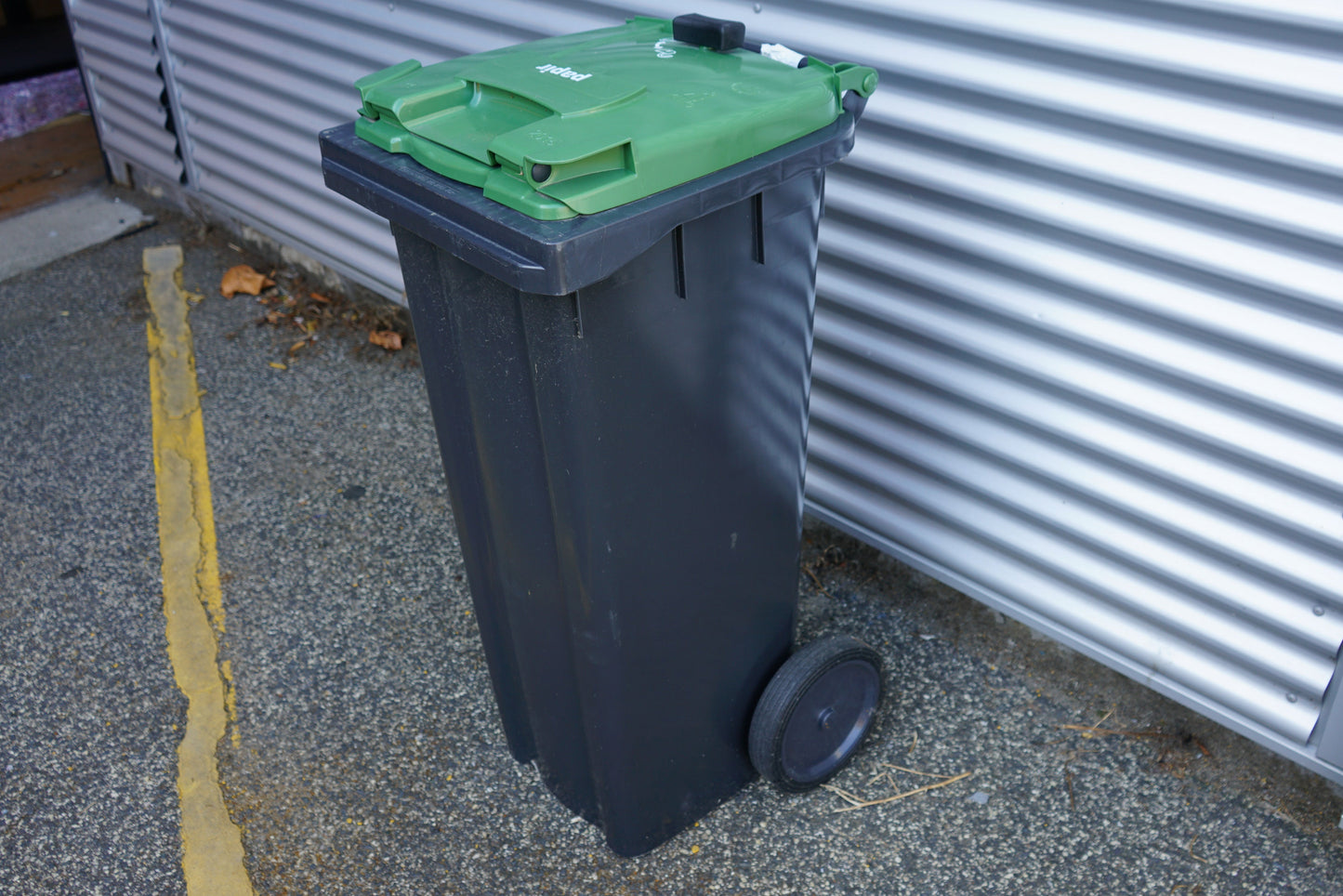 Grøn affaldscontainer på 140 liter med hjul set fra højre side – solid udendørs container til affaldshåndtering