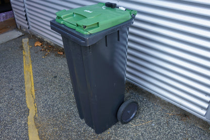 Grøn affaldscontainer på 140 liter med hjul set fra højre side – solid udendørs container til affaldshåndtering