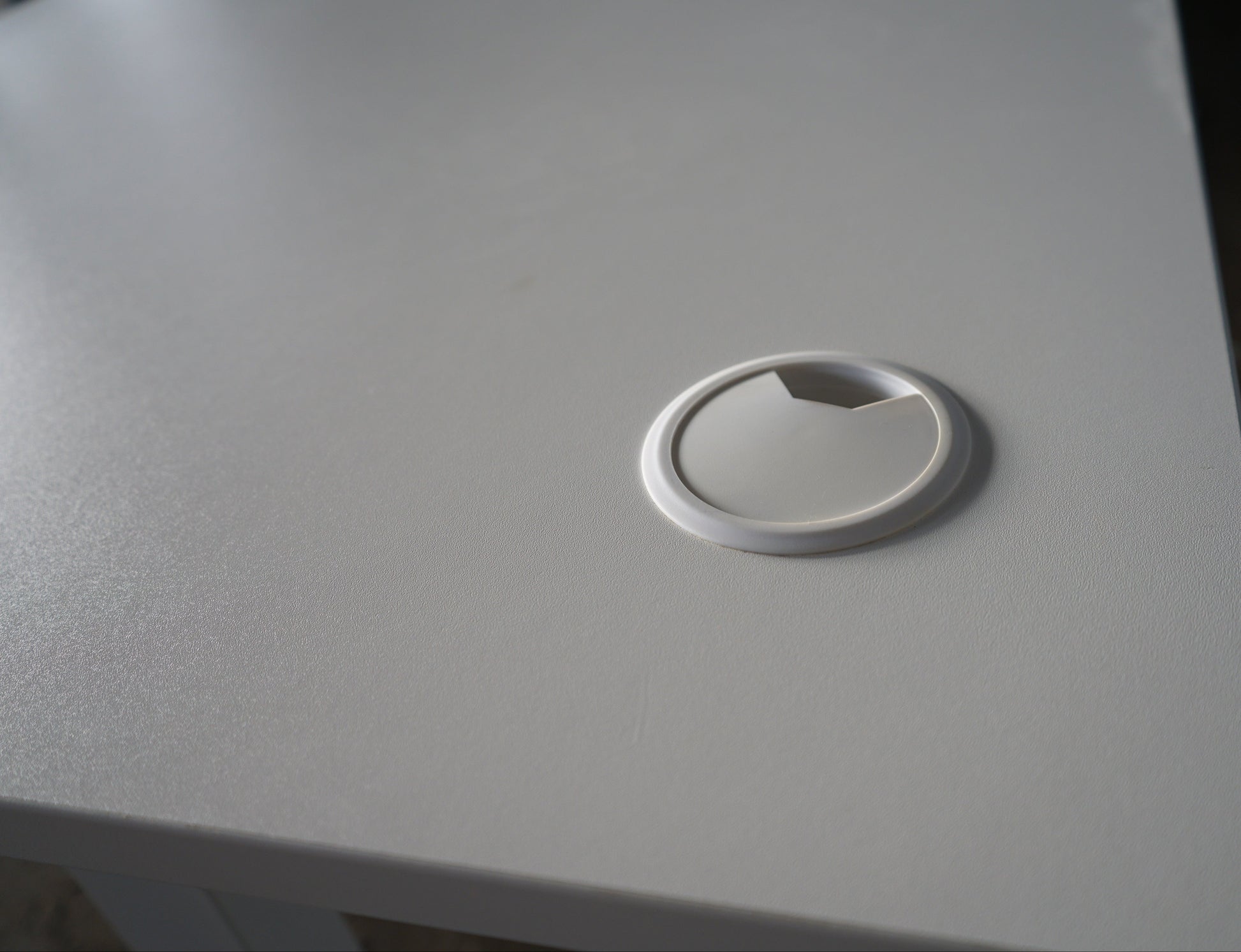 Kabelgennemføring på AJ Products hæve-sænkebord, der giver nem og organiseret kabelhåndtering.