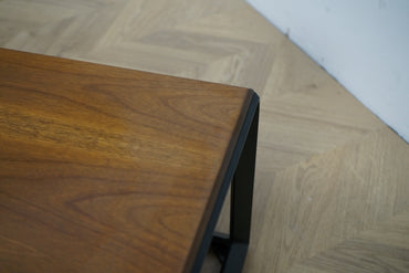 Close up af AM.PM Nolia sofabordets valnøddefiner og sorte metalstruktur