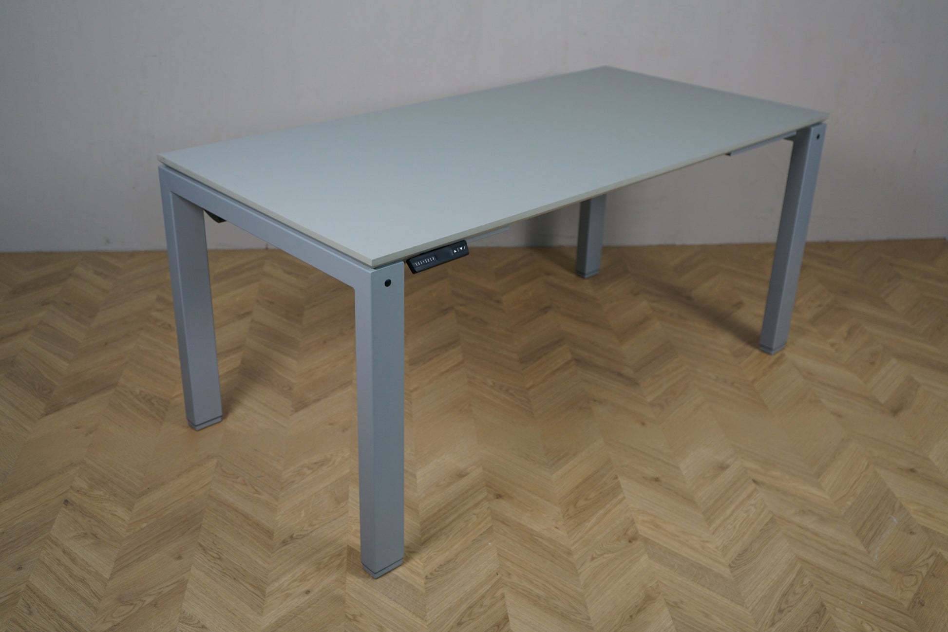 Arnehus hæve-sænkebord i grå set fra skrå vinkel, helt nyt 160x80 cm skrivebord med justerbart stel.