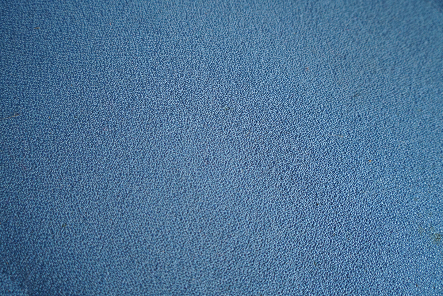 Close-up af blå polstring og detaljer på kontorstol med høj ryg og ergonomisk design.