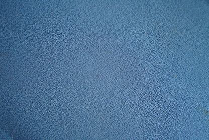 Close-up af blå polstring og detaljer på kontorstol med høj ryg og ergonomisk design.