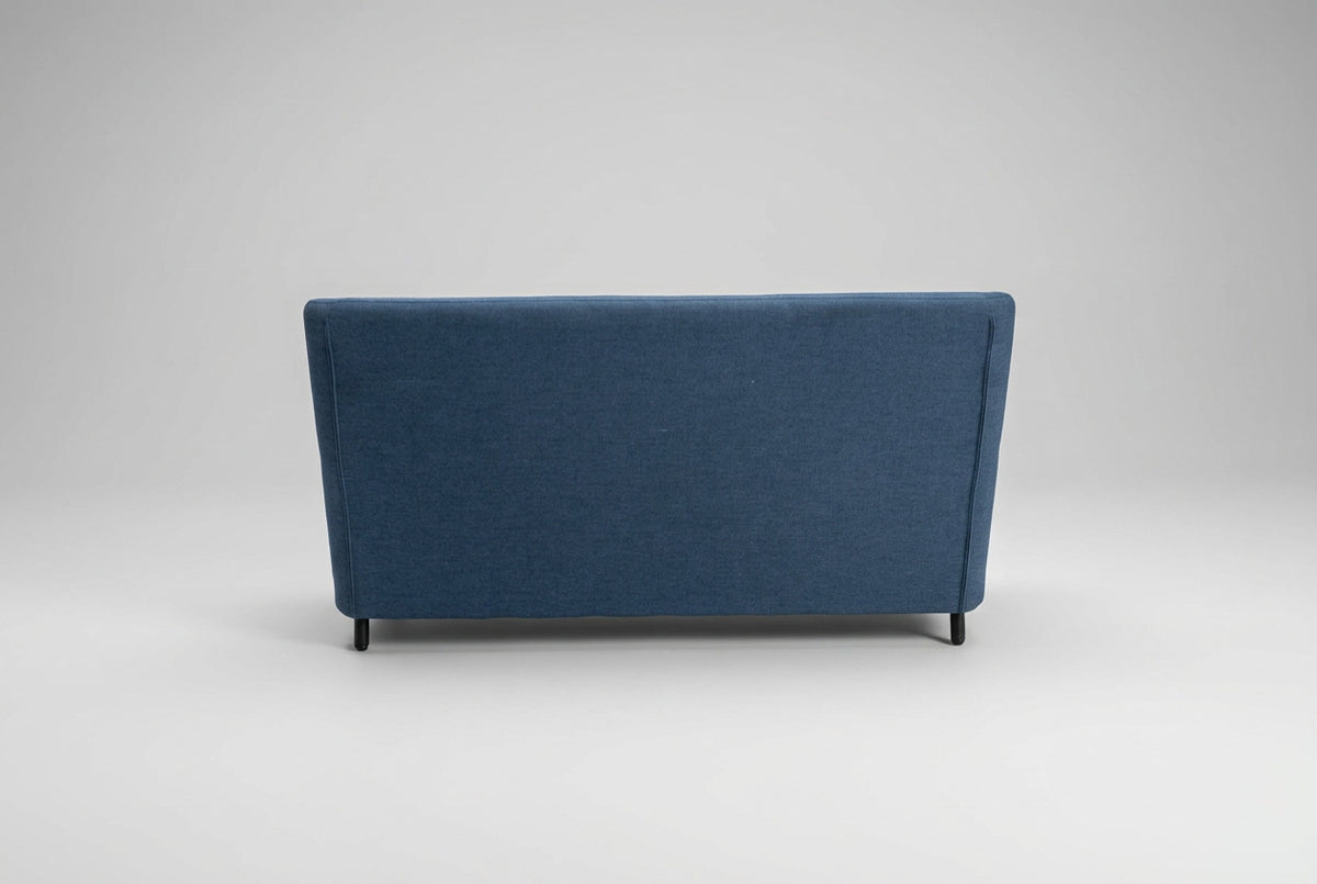 Bolia loungesofa set bagfra med højt blåpolstret ryglæn og slanke sorte ben til loungeområde og venteværelse.