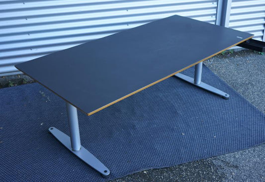 Bondo hæve-sænkebord 180x90 cm med sort linoleum og affasede kanter, set fra skrå vinkel med Linak-stel og kabelbakke.
