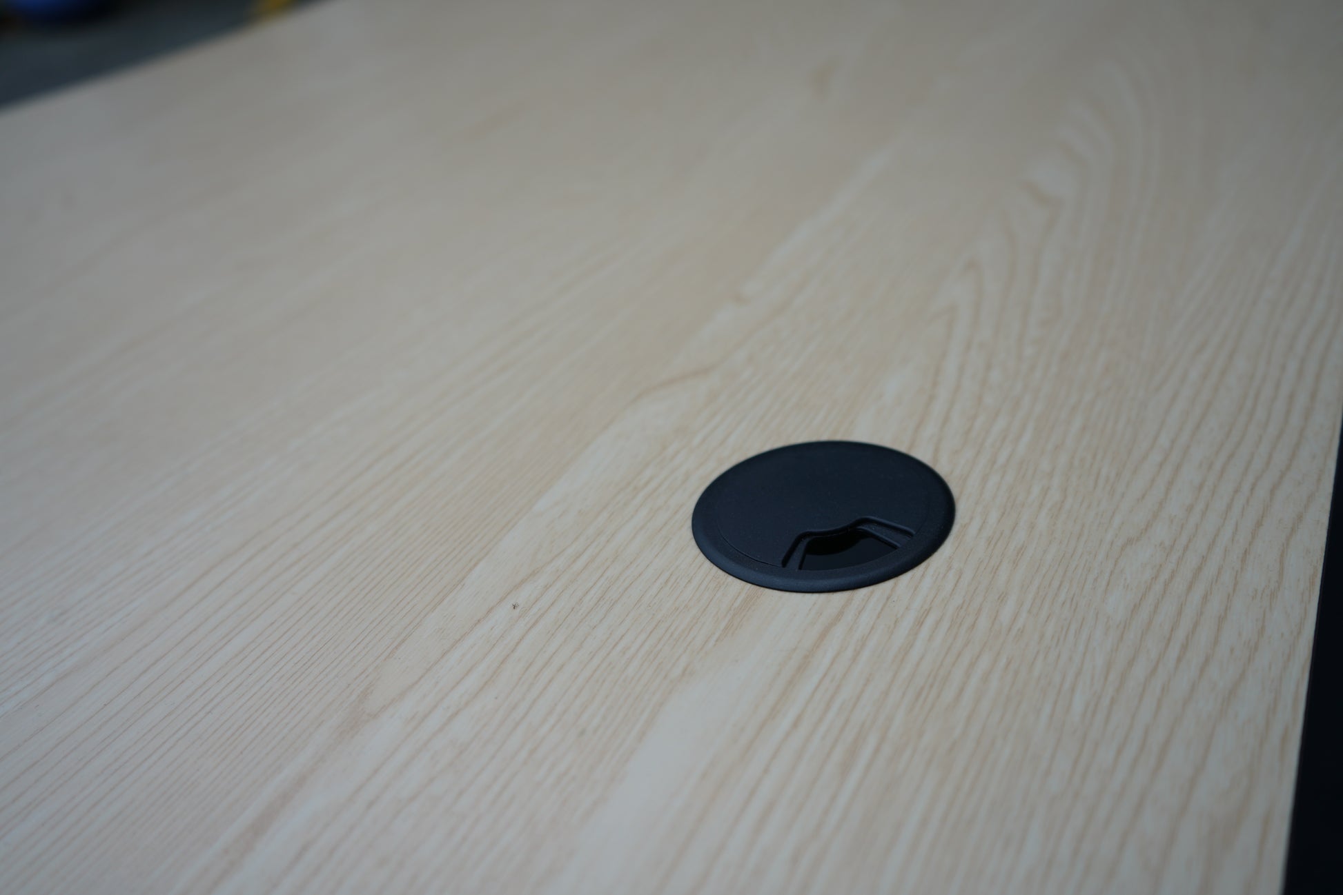 Nærbillede af kabelgennemføring på Cube Design hæve-sænkebord i egetræ – praktisk løsning til kabelføring og orden på skrivebordet.