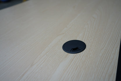 Nærbillede af kabelgennemføring på Cube Design hæve-sænkebord i egetræ – praktisk løsning til kabelføring og orden på skrivebordet.