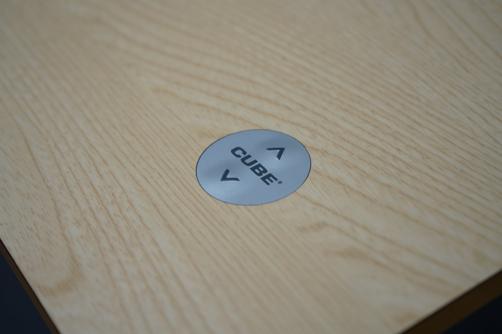 Nærbillede af betjeningsknap til Cube Design hæve-sænkebord i egetræ med op- og ned-funktion.