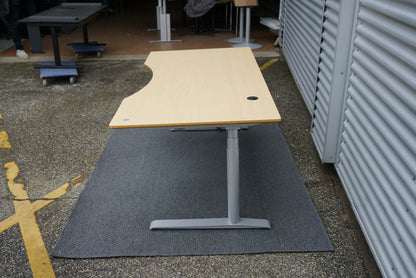 Cube Design hæve-sænkebord i egetræ set fra siden, der viser bordets ergonomiske form og solide hæve-sænkestel.