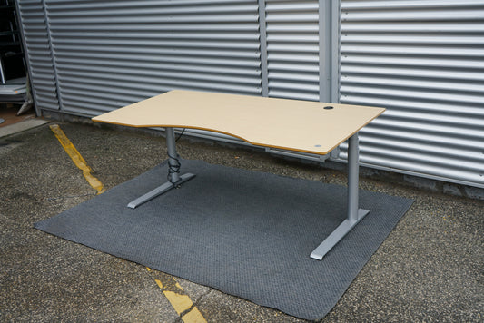 Cube Design hæve-sænkebord i egetræ set fra skrå vinkel med mavebue, sølvgråt stel og kabelgennemføring, 180x90 cm.