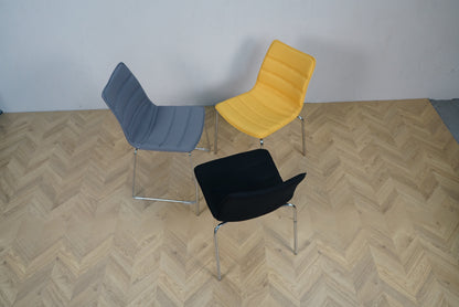 Sideview af tre Cube Design stole i grå, sort og gul med polstret sæde og krom stel