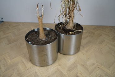 Close up af cylindrisk metalpotte i metal med hjul og rå overflade