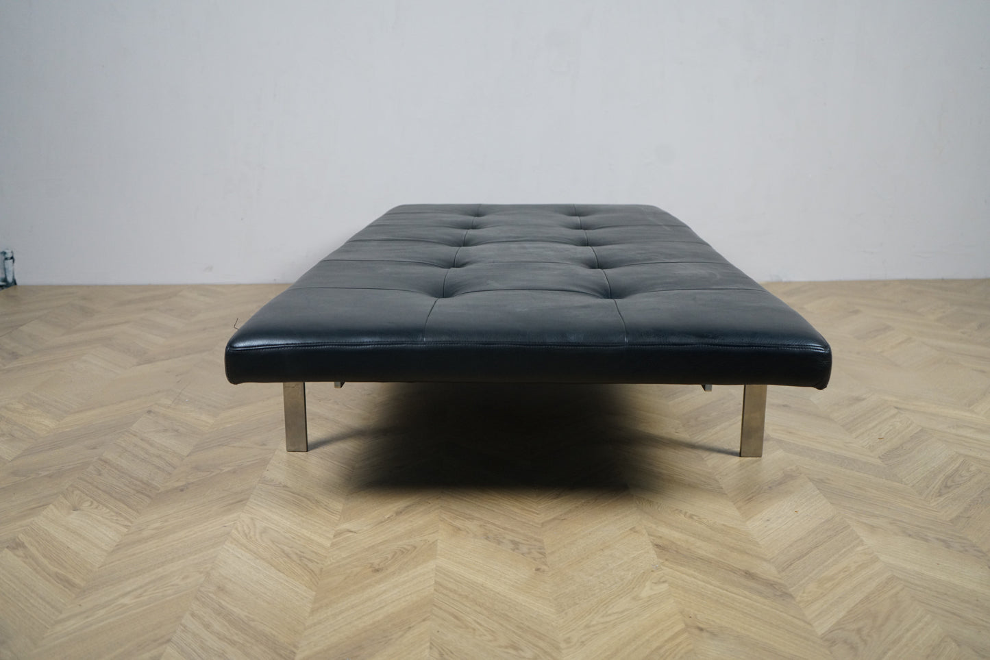 dagseng i sort læder, set forfra med forkromede stålben.