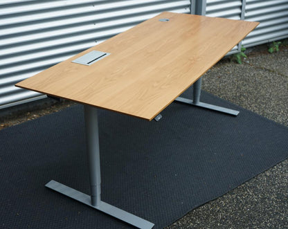 Dencon Delta hæve-sænkebord 180x80 i træfarvet finish set fra skrå vinkel.