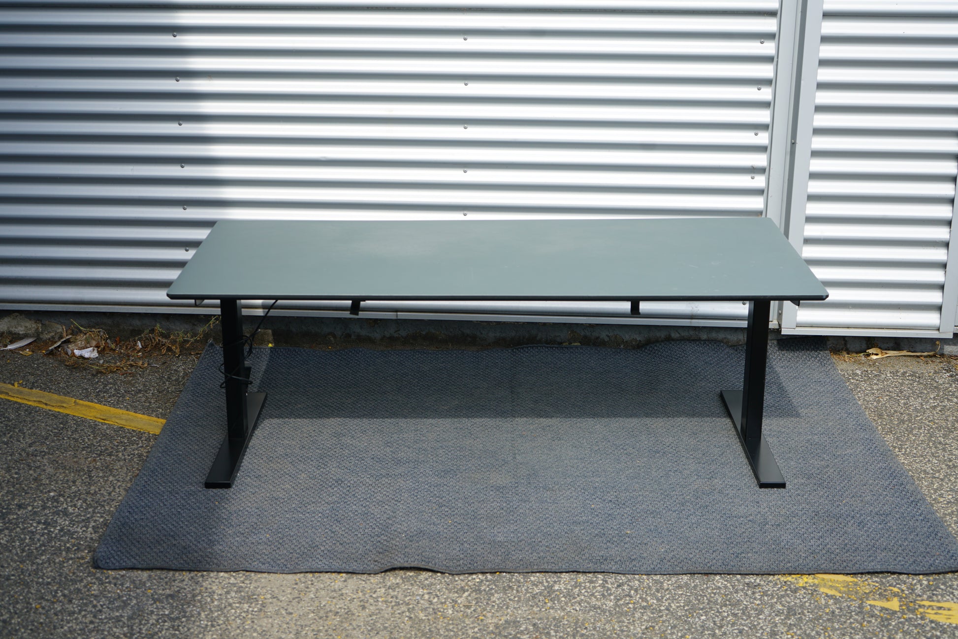 Dencon hæve-sænkebord med mørkegrå bordplade og sorte ben set bagfra – stilrent og ergonomisk hæve-sænkebord