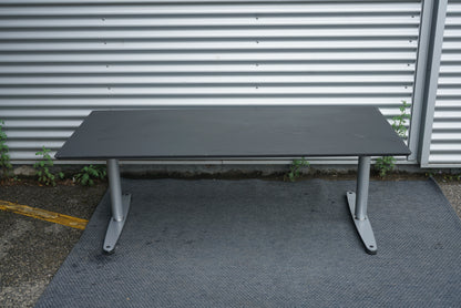 Dencon hæve-sænkebord 180x80 cm sort set bagfra med kabelbakke og justerbare ben.