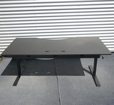 Dencon hæve-sænkebord i sort set bagfra med elektrisk stel og kabelbakke. Robust danskproduceret skrivebord i mål 180x90 cm med Linak-motor.