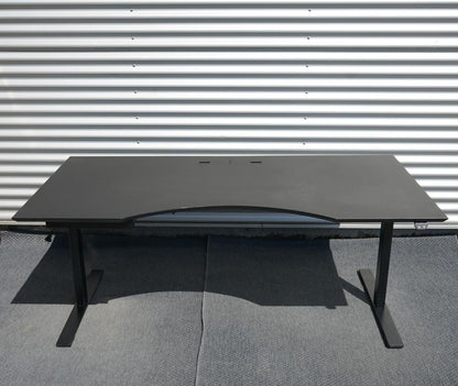 Dencon hæve-sænkebord i sort med linoleumsbordplade og elegant mavebue, set forfra. Elektrisk højdejusterbart bord 180x90 cm med kabelgennemføring.