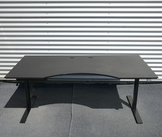 Dencon hæve-sænkebord i sort med linoleumsbordplade og elegant mavebue, set forfra. Elektrisk højdejusterbart bord 180x90 cm med kabelgennemføring.
