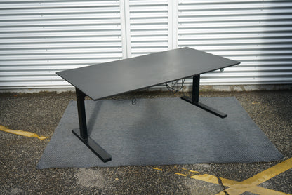 Ergonomisk Dencon skrivebord med sort bordplade og Linak stel – set fra skrå vinkel.