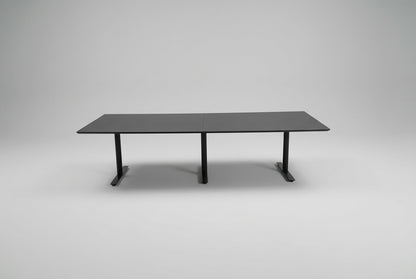Dencon mødebord i sort linoleum på 280 x 110 cm med tre sorte T-formede ben set forfra.
