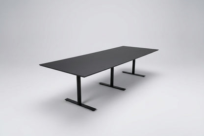Dencon mødebord i sort linoleum med affaset kant og sort metalstel med tre T-formede ben set skråt.