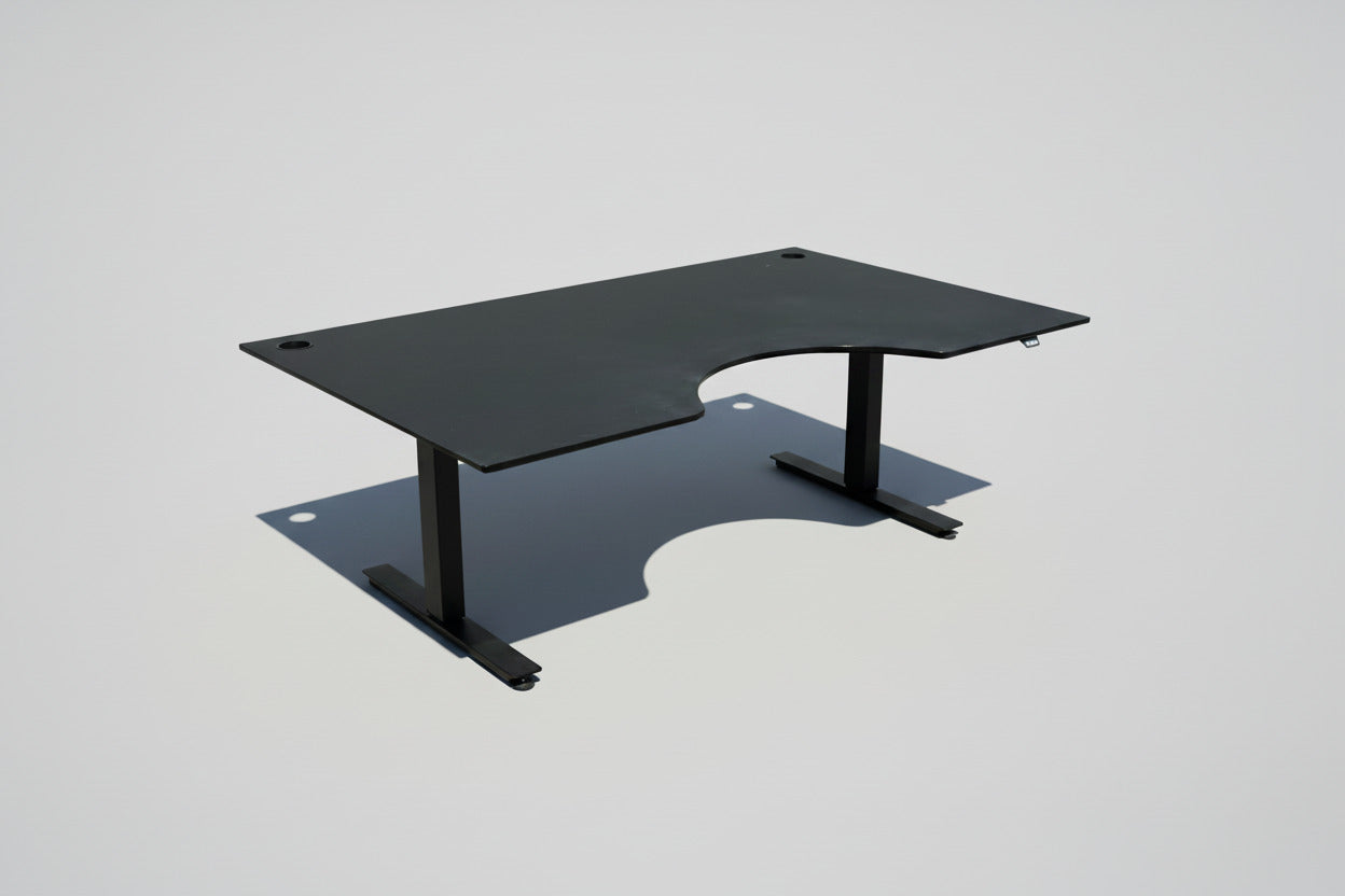EFG hæve-sænkebord 180x110 cm med sort linoleumsbordplade, ergonomisk mavebue og sort stel set fra skrå vinkel.