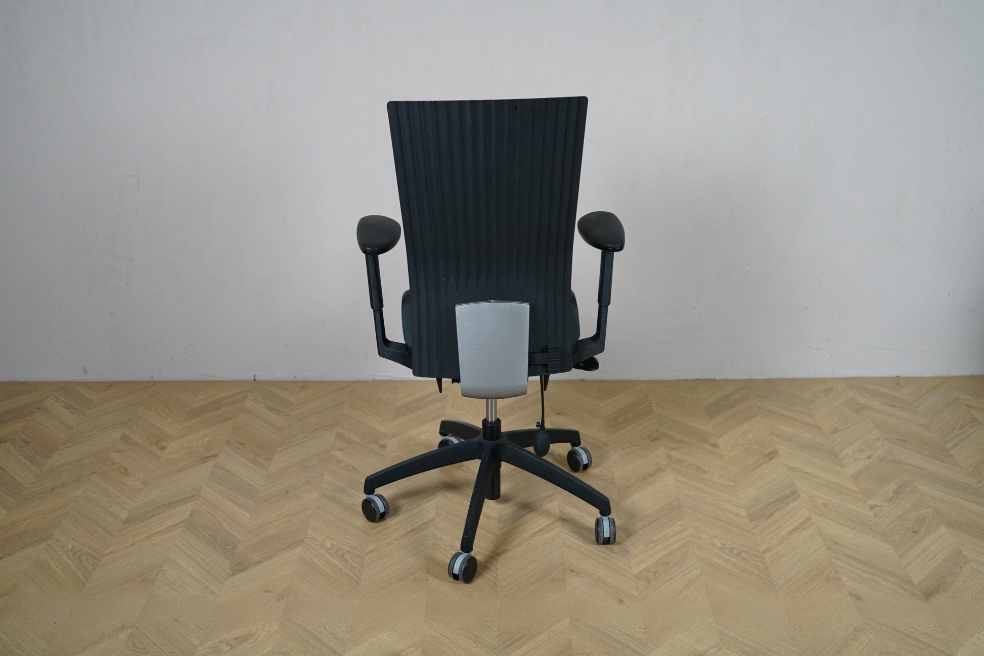 EFG kontorstol set bagfra med sort ryglænspanel, armlæn og stabilt sort fodkryds.