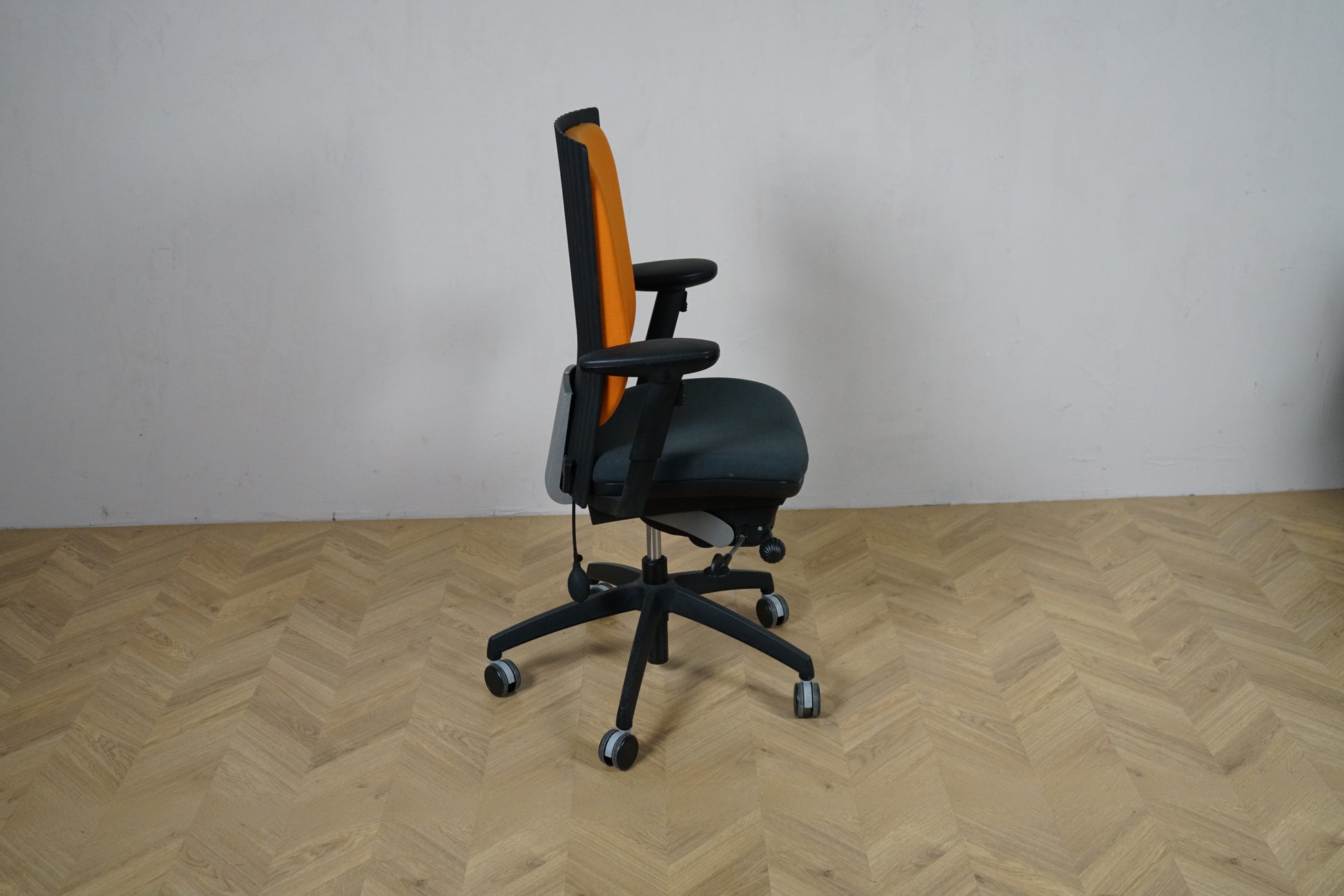 EFG kontorstol set fra siden med orange ryglæn, armlæn og ergonomisk sæde på sort fodkryds.