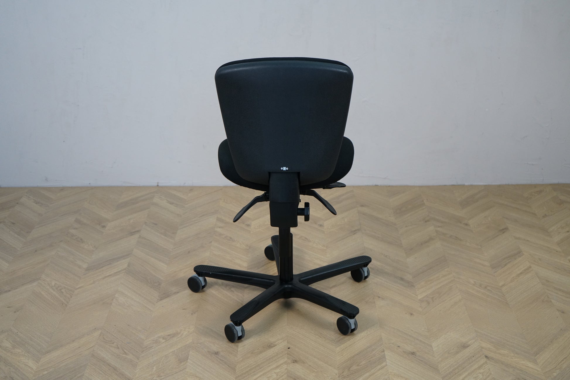 EFG kontorstol med lav ryg og sort fodkryds set bagfra, med justerbar lændestøtte.