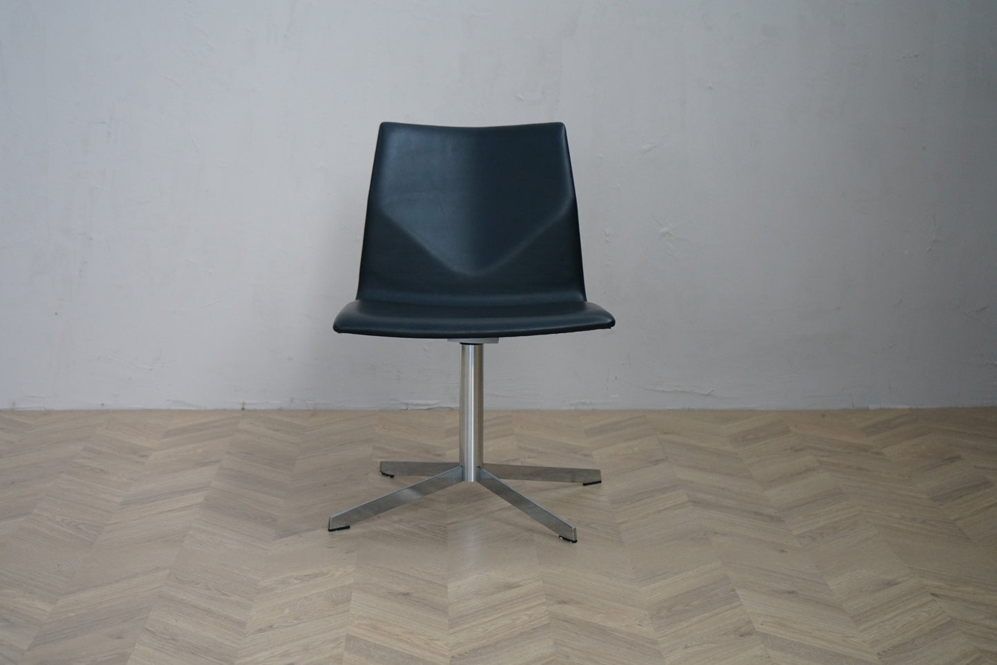 Four Design Four Cast loungestol i sort læder med drejefod i krom set forfra