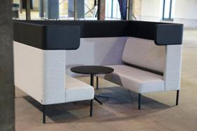 Indvendigt kig i Four Design FourUs Booth med grå polstring og centralt placeret sort bord – ideel til møde- og pausezoner på kontoret
