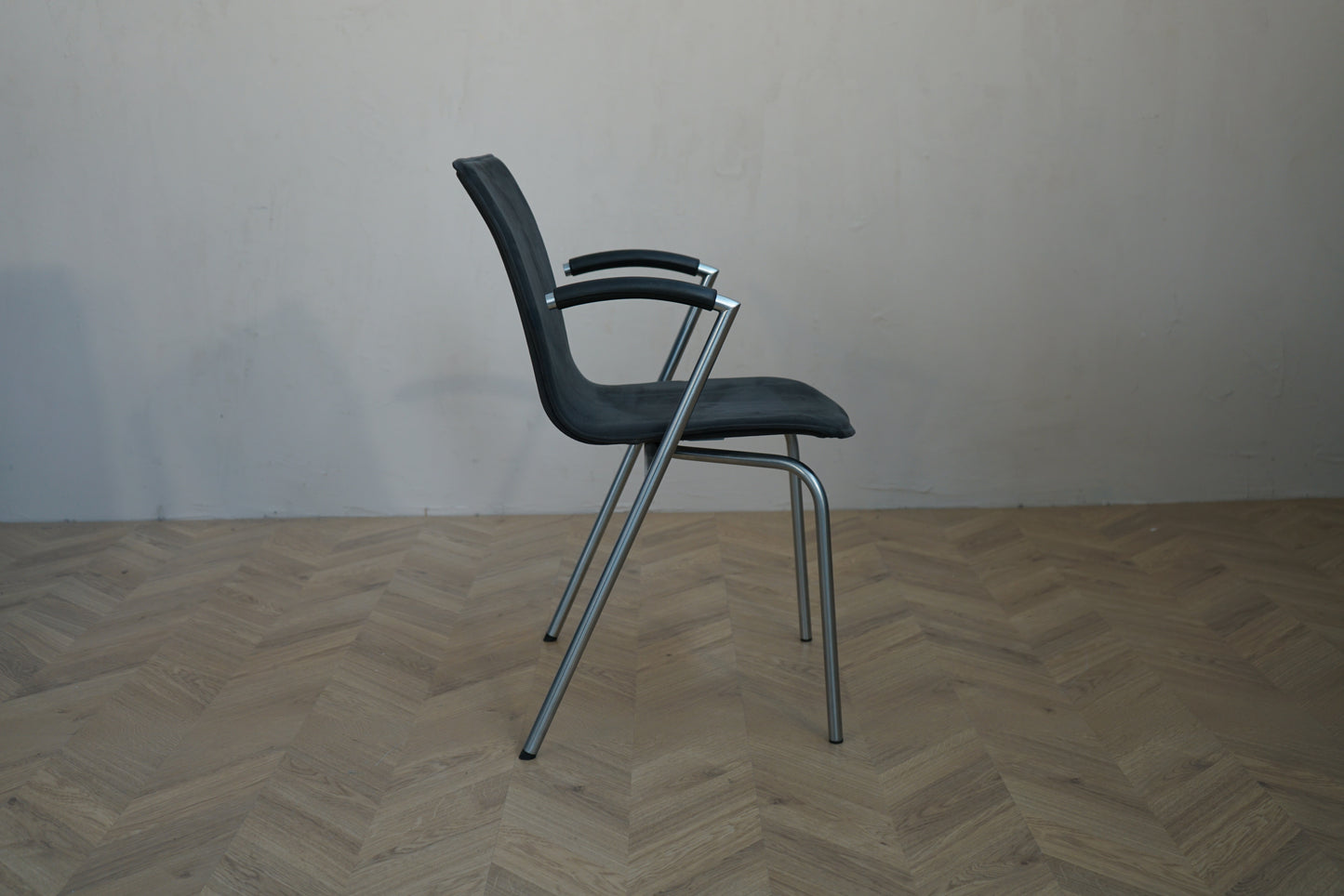 Four Design G2 mødestol set fra siden med fuldpolstret sæde, armlæn og stel i børstet stål.