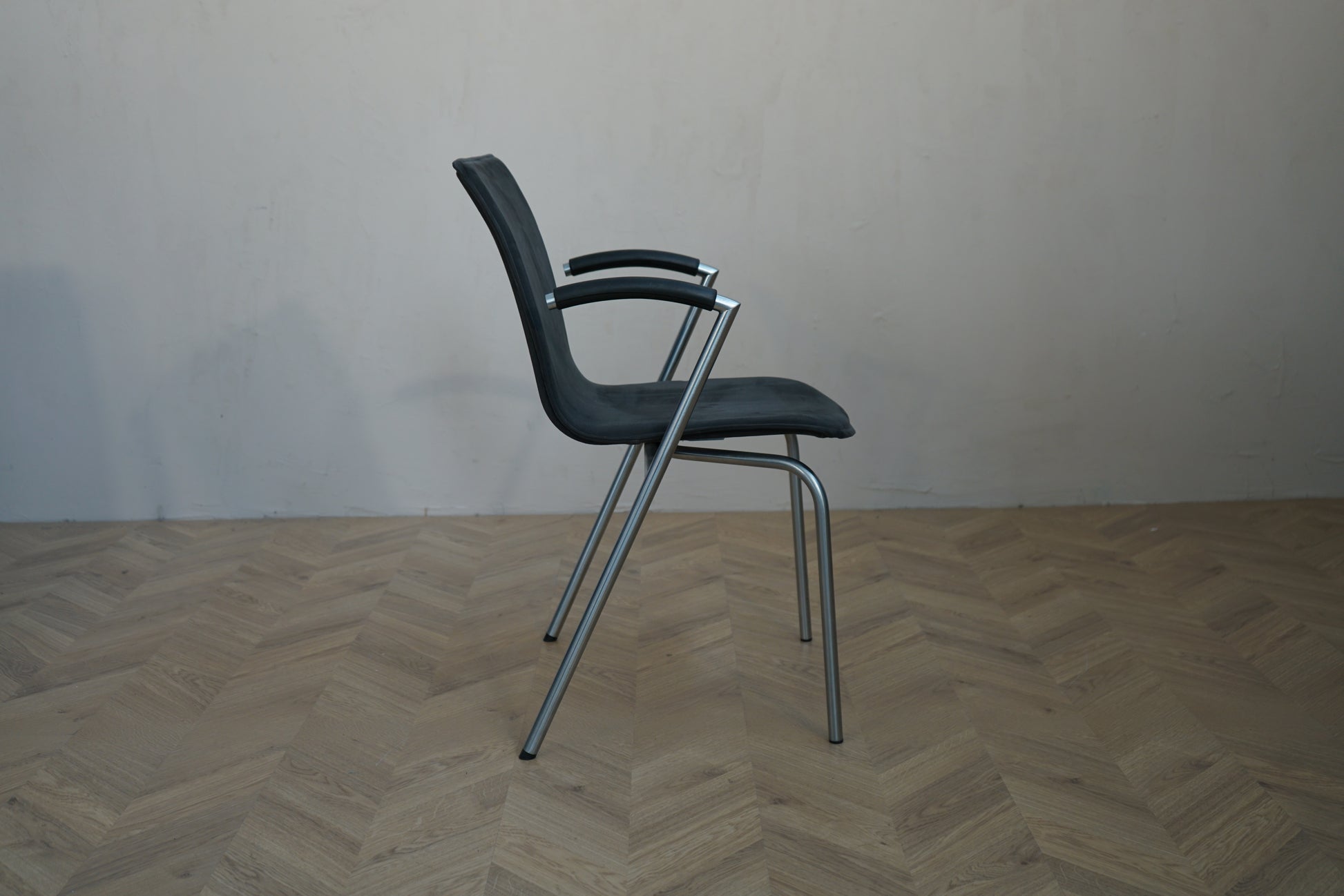 Four Design G2 mødestol set fra siden med fuldpolstret sæde, armlæn og stel i børstet stål.