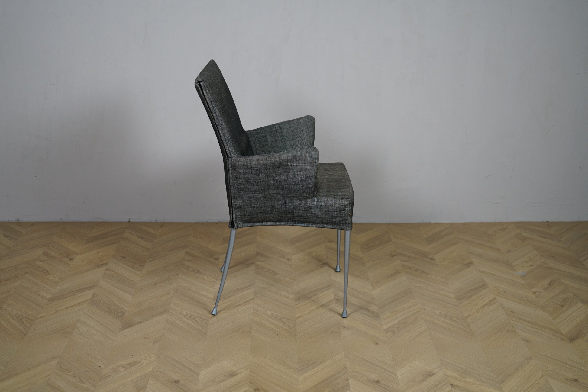 Grå loungestol set fra siden med højt ryglæn og armlæn