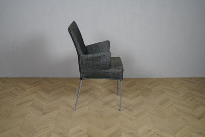 Grå loungestol set fra siden med højt ryglæn og armlæn