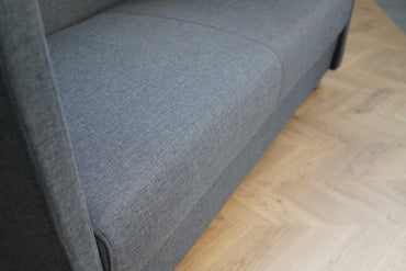 Close up af grå mødesofa med polstret stof og høj ryg