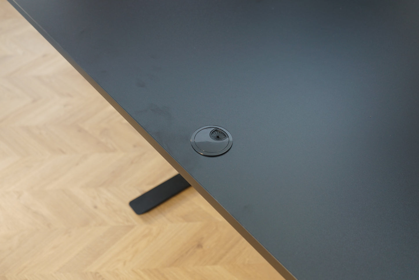 Close up af sort laminat bordplade med kabelgennemføring og affaset kant