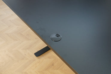 Close up af sort laminat bordplade med kabelgennemføring og affaset kant